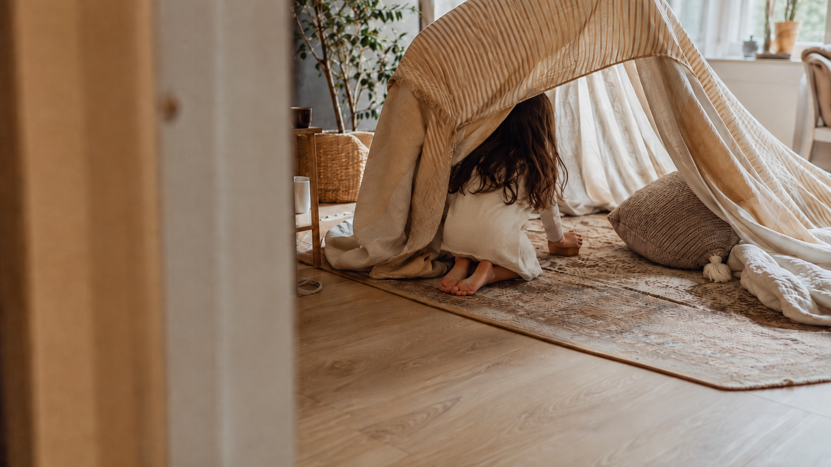 A child building a blanket fort in a calm, warmly lit room